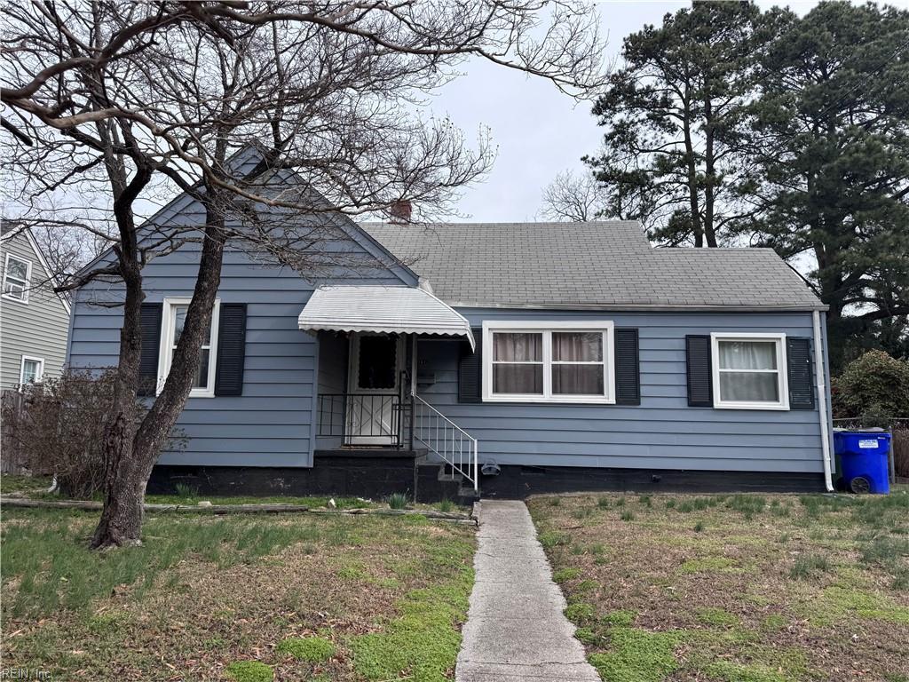 view of front of house with a shingled roof and a front lawn