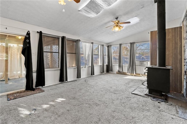 unfurnished sunroom featuring lofted ceiling, a ceiling fan, and a wood stove