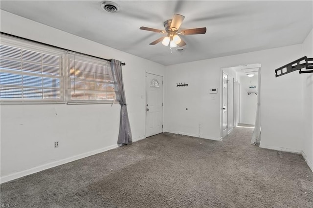 carpeted spare room featuring visible vents, baseboards, and a ceiling fan