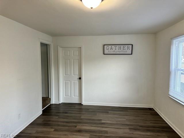 unfurnished room with dark wood-style flooring and baseboards