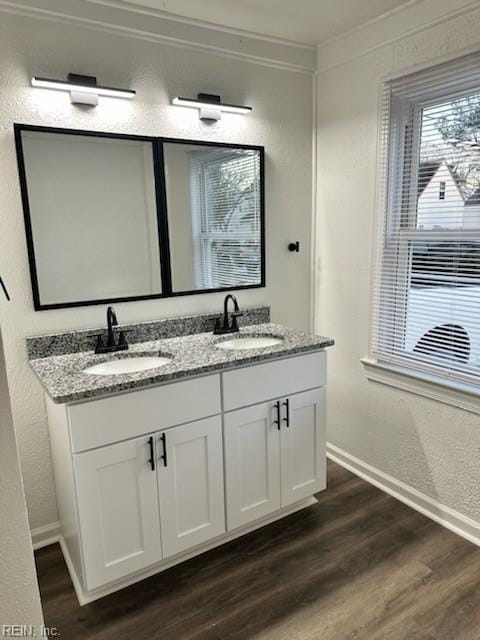 bathroom with double vanity, crown molding, a sink, and wood finished floors