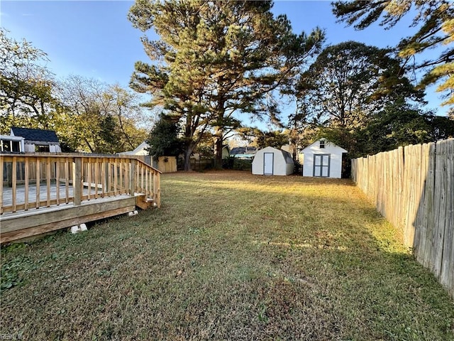 view of yard with a shed, a deck, a fenced backyard, and an outdoor structure