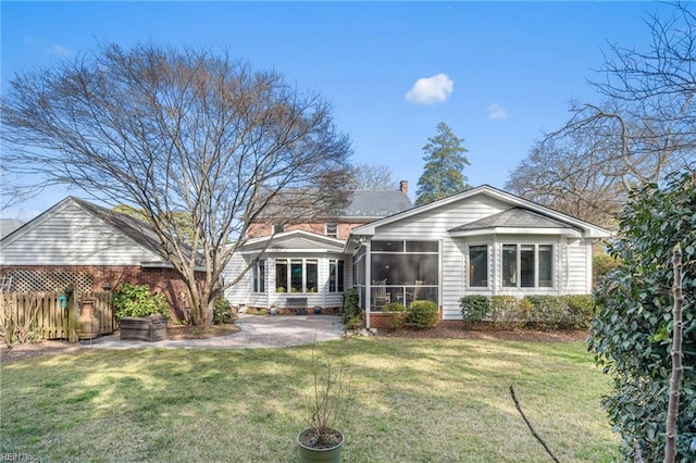 rear view of property with a patio, fence, a sunroom, a chimney, and a lawn