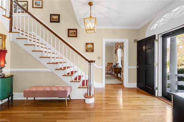 entryway featuring crown molding, baseboards, light wood-type flooring, and a chandelier