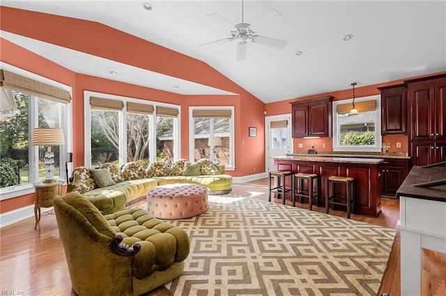 living room with light wood finished floors, plenty of natural light, baseboards, and lofted ceiling