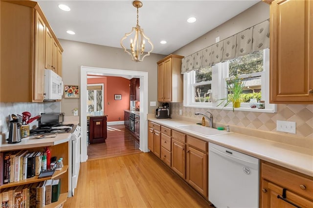 kitchen featuring light wood-style flooring, white appliances, light countertops, and a sink