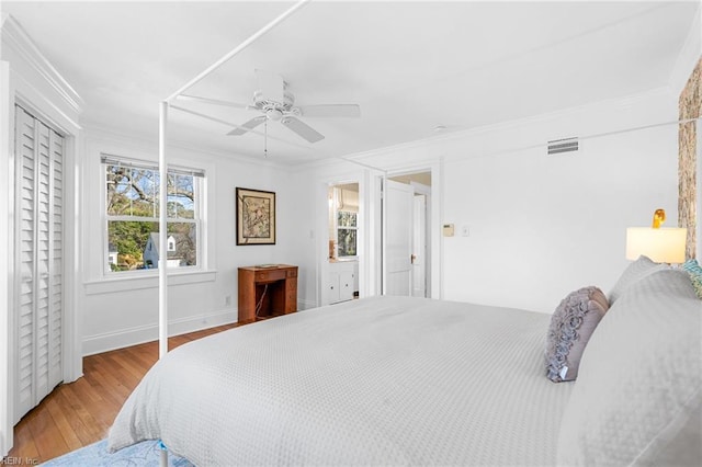 bedroom featuring visible vents, baseboards, ceiling fan, ornamental molding, and wood finished floors