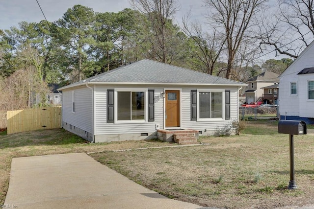 bungalow-style home featuring roof with shingles, crawl space, a front yard, and fence