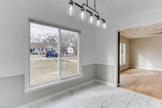 unfurnished dining area featuring baseboards, marble finish floor, and a healthy amount of sunlight