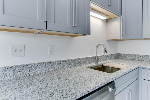 kitchen featuring dishwasher, light stone counters, and a sink