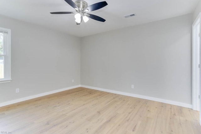 empty room with baseboards, visible vents, ceiling fan, and wood finished floors