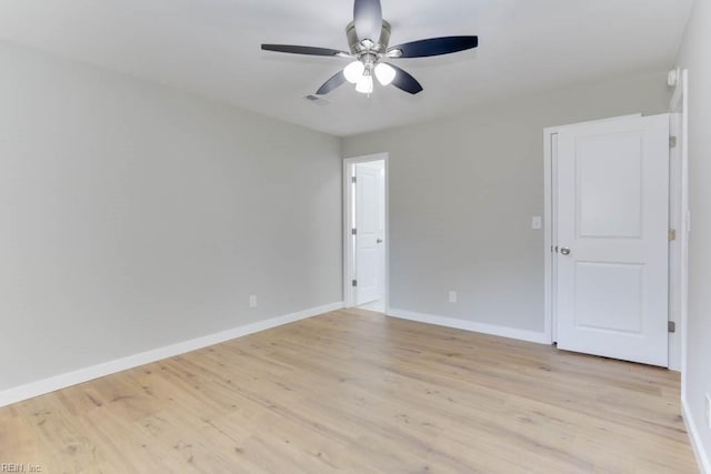 empty room with a ceiling fan, light wood-style flooring, and baseboards