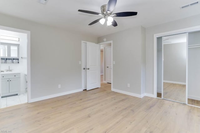 unfurnished bedroom with light wood-style floors, connected bathroom, visible vents, and baseboards