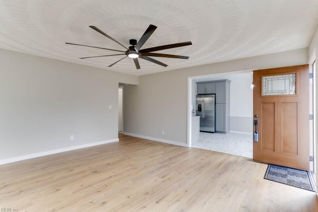 empty room featuring light wood-type flooring, ceiling fan, and baseboards