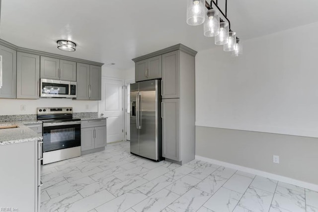 kitchen with baseboards, marble finish floor, appliances with stainless steel finishes, gray cabinets, and light stone countertops