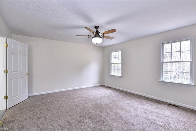 carpeted empty room featuring a ceiling fan, baseboards, visible vents, and a textured ceiling