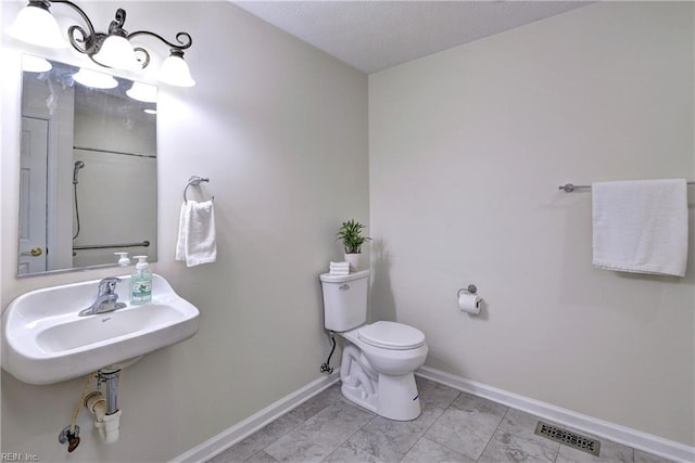 bathroom with a sink, visible vents, baseboards, and toilet