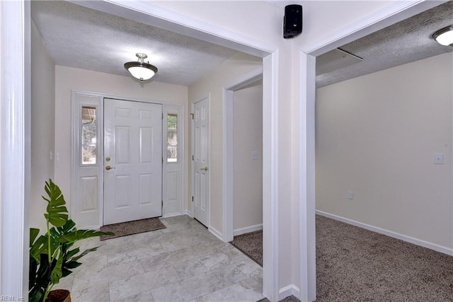 entryway with baseboards, a textured ceiling, and light carpet