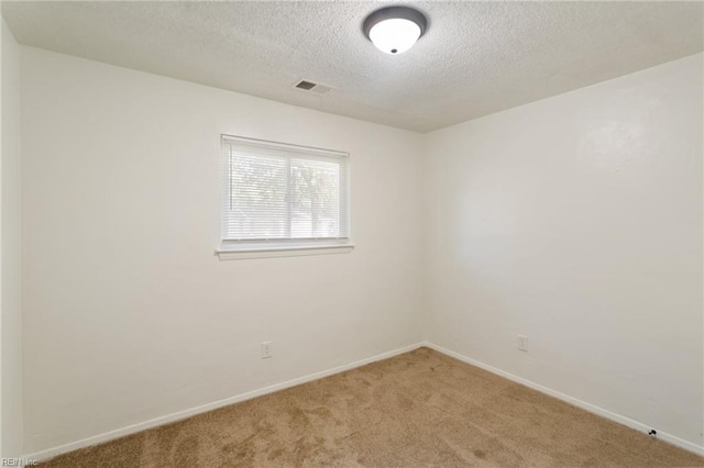 carpeted spare room with a textured ceiling and baseboards