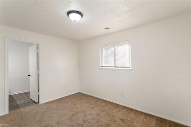 carpeted spare room featuring baseboards and a textured ceiling