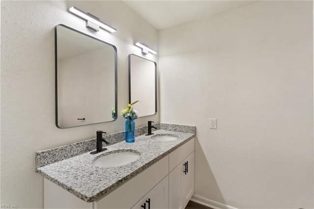 bathroom featuring a sink, baseboards, and double vanity