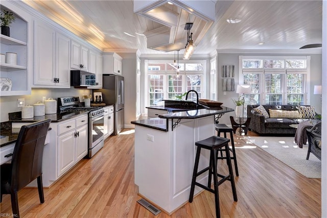 kitchen featuring a kitchen bar, visible vents, open shelves, stainless steel appliances, and crown molding