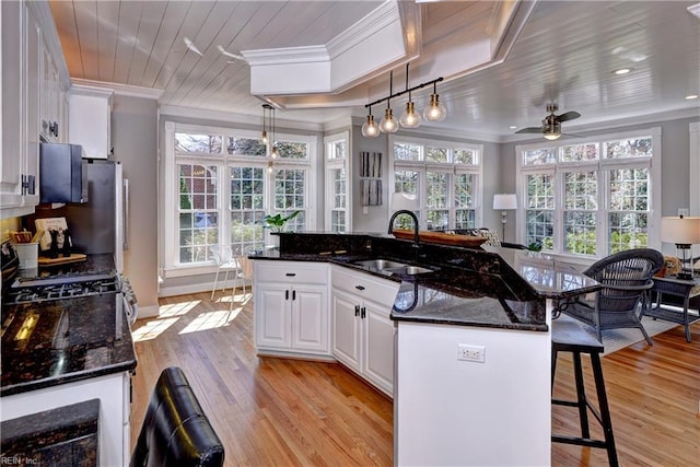 kitchen featuring ornamental molding, wooden ceiling, white cabinetry, and a sink