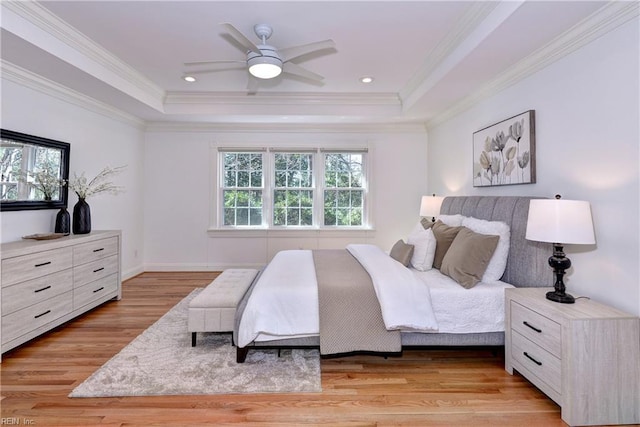 bedroom with light wood-type flooring, a tray ceiling, multiple windows, and crown molding