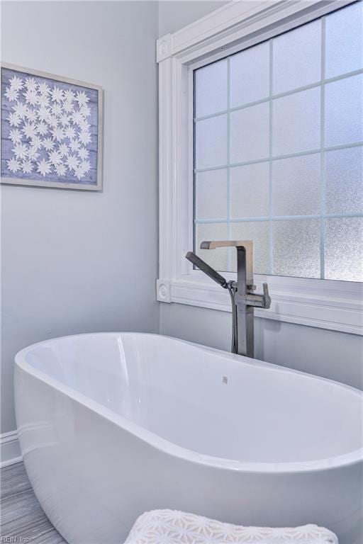 full bath featuring a freestanding tub and baseboards