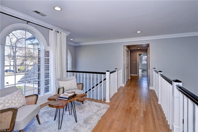 sitting room with visible vents, an upstairs landing, light wood-style flooring, ornamental molding, and recessed lighting