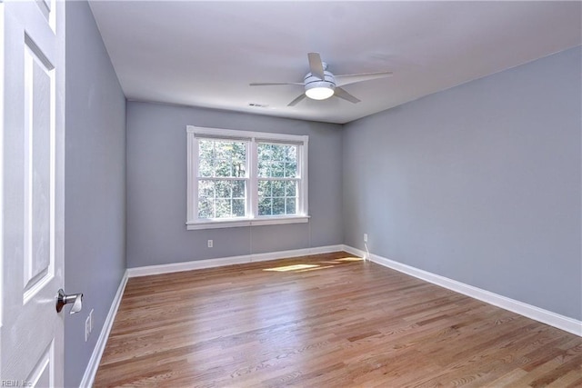 spare room with baseboards, ceiling fan, and wood finished floors