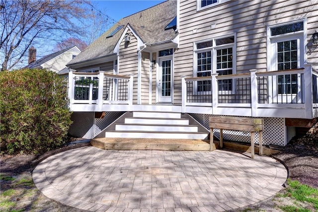 entrance to property with a deck and roof with shingles