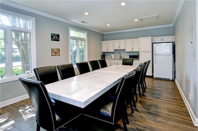 dining space with dark wood finished floors, a healthy amount of sunlight, and crown molding