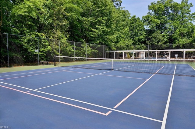 view of tennis court featuring community basketball court and fence