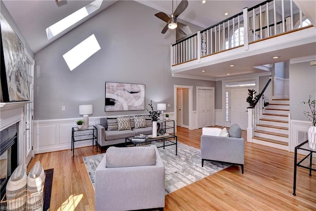 living area featuring stairs, a skylight, wood finished floors, and a high end fireplace