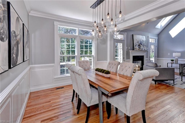 dining area with visible vents, light wood-style flooring, wainscoting, and ornamental molding