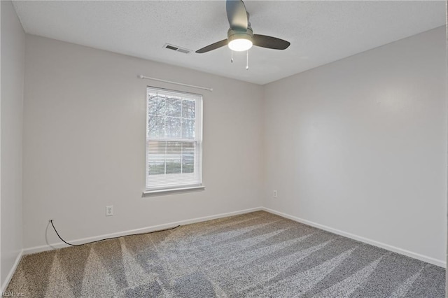 empty room with carpet floors, visible vents, a textured ceiling, and baseboards