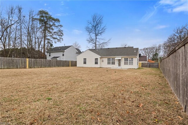 rear view of house with a fenced backyard and a lawn