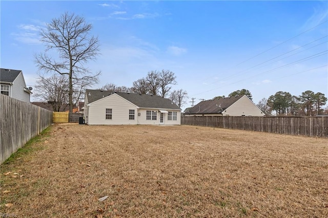 rear view of property featuring a yard and a fenced backyard