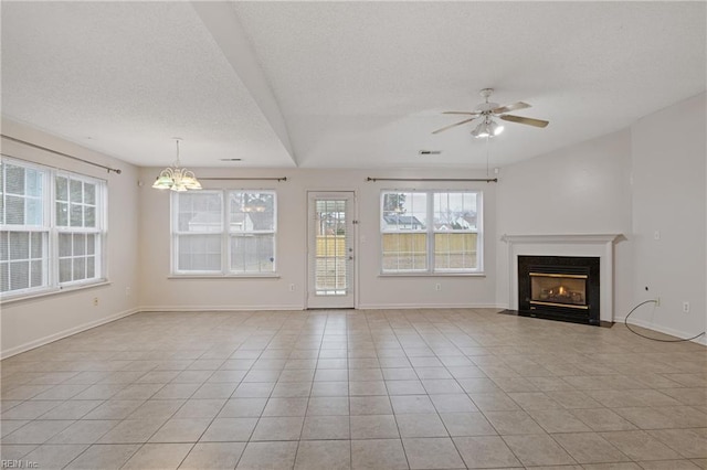 unfurnished living room featuring baseboards, a fireplace with flush hearth, light tile patterned flooring, a textured ceiling, and ceiling fan with notable chandelier