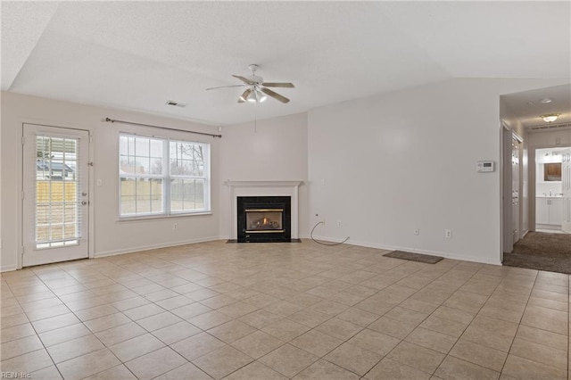 unfurnished living room with light tile patterned floors, lofted ceiling, visible vents, a fireplace with flush hearth, and a ceiling fan