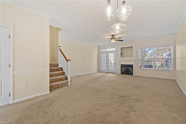 unfurnished living room featuring stairway, a fireplace, crown molding, and carpet floors