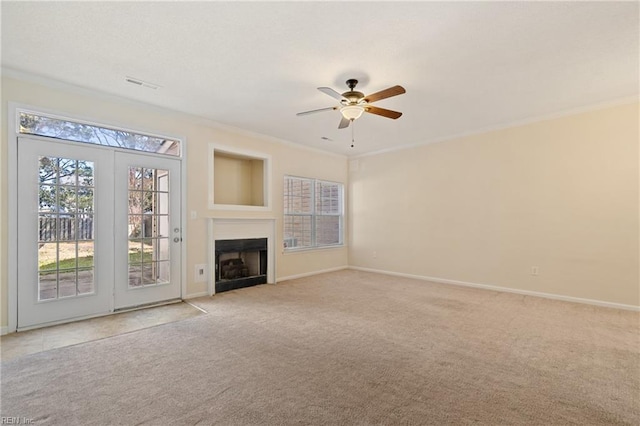 unfurnished living room with baseboards, a fireplace, ceiling fan, ornamental molding, and light carpet