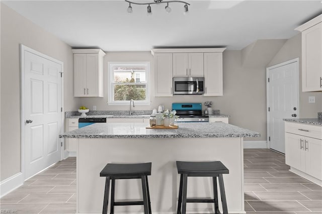 kitchen featuring stainless steel appliances, wood finish floors, a sink, and a kitchen breakfast bar