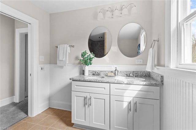 full bath featuring double vanity, a wainscoted wall, a sink, and tile patterned floors