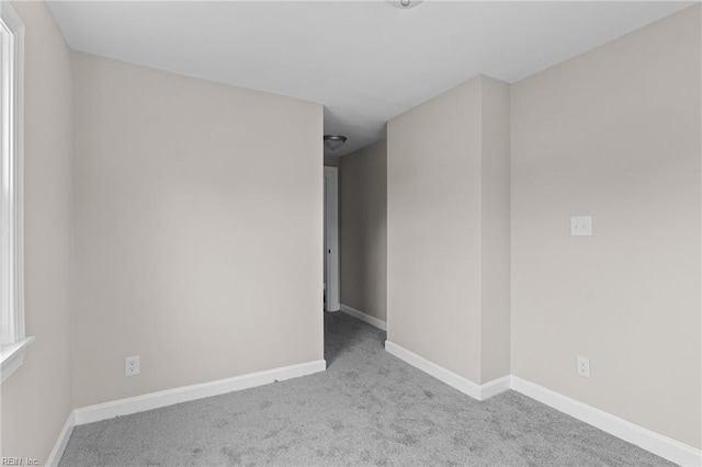 carpeted spare room featuring baseboards