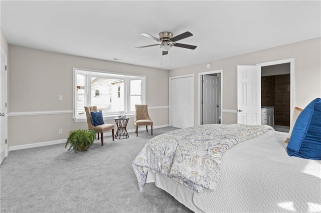 carpeted bedroom with ensuite bath, two closets, a ceiling fan, and baseboards