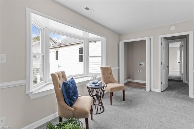 sitting room with carpet floors, visible vents, plenty of natural light, and baseboards