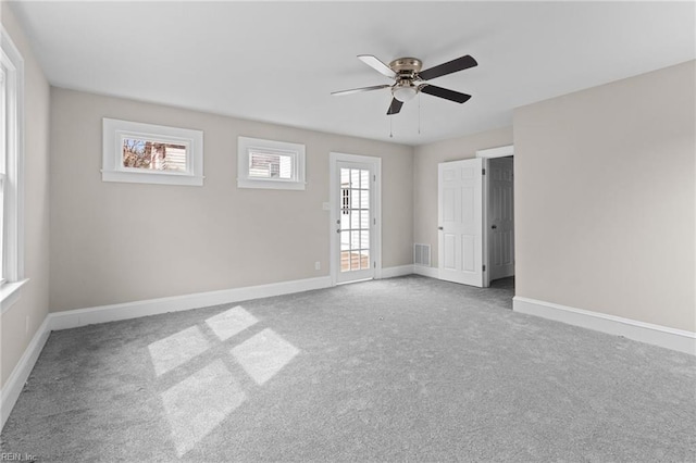 carpeted empty room featuring visible vents, a ceiling fan, and baseboards