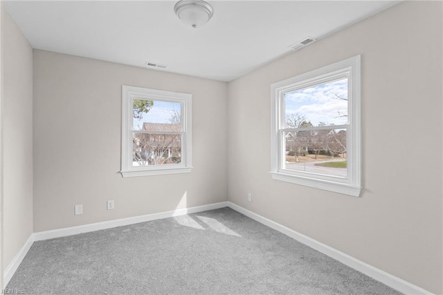 spare room featuring carpet floors, visible vents, and baseboards